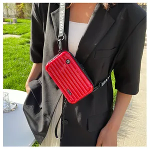 Close-up of a red mini suitcase crossbody bag with Forever Young strap on a model