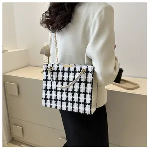 Détail du sac cabas classique en tweed noir et blanc avec chaîne dorée et poignée en cuir