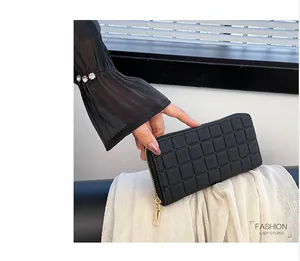 Detail of black checkered leather clutch wallet with gold zipper held by a model