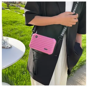 Close-up of pink mini suitcase crossbody bag with Forever Young lettered strap