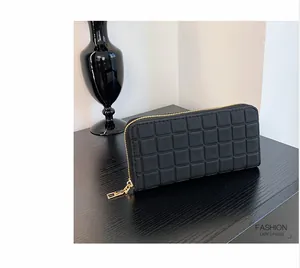 Detail of black long wallet with checkered texture and gold zipper on a wooden surface