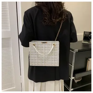 Sac bandoulière tendance en tweed blanc montrant la texture tissée sur le mannequin