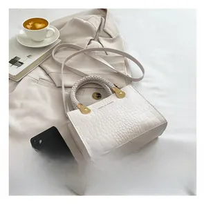 White croc-effect crossbody bag with woven handle shown next to a phone for size reference