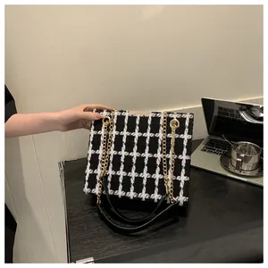 Détail d'un sac cabas en tweed à carreaux avec chaîne dorée dans un bureau chic