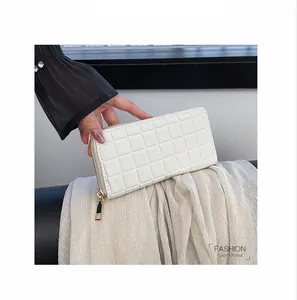 Detail of cream long clutch purse showing square quilted texture and gold zipper
