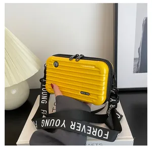 Detailed macro view of the bright yellow mini suitcase hardshell bag with logo