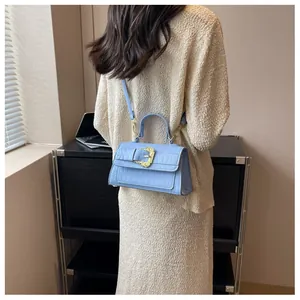 Close-up of light blue croc-embossed crossbody bag featuring vintage gold buckle