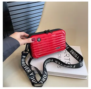 Detail of red suitcase style hard shell bag with Forever Young strap on a book