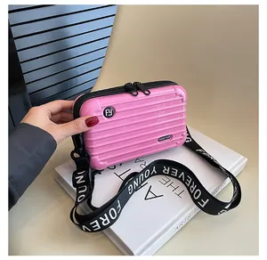 Close-up of pink hardshell mini suitcase bag with Forever Young printed fabric strap