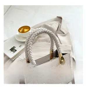 Detail of white crocodile texture handbag with unique braided top handle and gold hardware