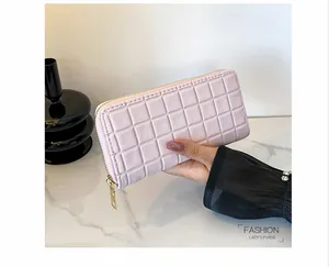 Close-up of pink long purse with square embossed pattern and gold zipper detail