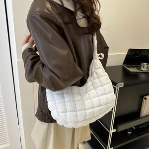 Close-up of a white quilted puffer shoulder bag with square stitching and soft cloud texture