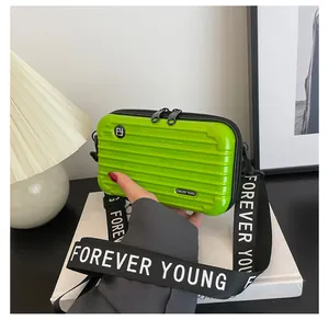 Detail of bright green mini hard shell crossbody bag with Forever Young strap