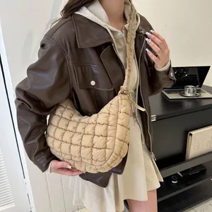 Detail of beige quilted crescent bag with soft textured pattern and knotted shoulder strap