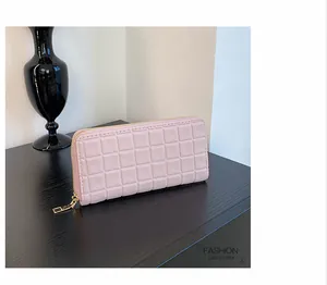 Detail of light pink long wallet featuring 3D grid embossed texture and gold zipper