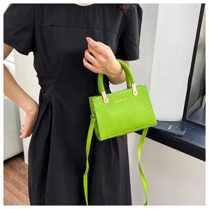 Detail of neon green crocodile texture handbag with woven handle and gold hardware