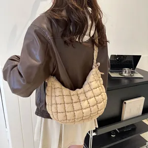 Detail of beige quilted puffer shoulder bag with a half-moon shape and square stitching