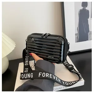 Detail of black mini suitcase crossbody bag with hard shell stripes and wide fabric strap