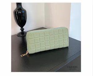 Detail view of mint green long wallet with textured grid pattern and gold zipper