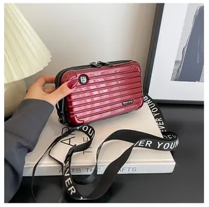 Detail of burgundy mini suitcase crossbody bag with Forever Young strap and rib texture