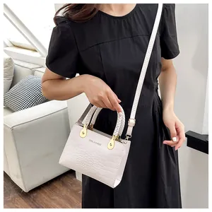 White crocodile pattern bag with braided handle and gold hardware on a lifestyle model