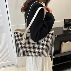 Detail of large houndstooth tote bag with leather straps on a fashion model
