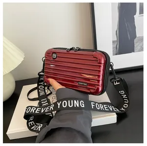 Detail of red hard-shell suitcase-style crossbody bag with Forever Young strap