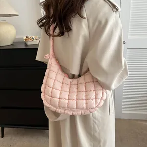 Sac à bandoulière matelassé rose avec texture bulle et forme de croissant sur modèle