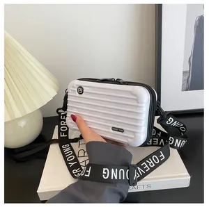 Close-up of white mini suitcase crossbody bag with Forever Young strap and hard shell