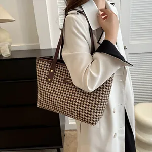 Lifestyle shot showing the large houndstooth tote bag worn as a shoulder bag