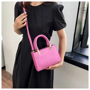 Detail of pink faux crocodile leather crossbody bag with woven handle and gold hardware