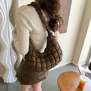 Gros plan d'un sac nuage matelassé marron avec bandoulière plissée porté par un mannequin