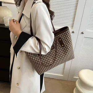 Detail of classic houndstooth tote bag showing brown leather trim and woven texture