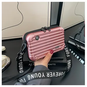 Pink suitcase-style mini crossbody bag in hardshell material with wide strap
