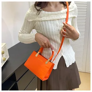 Orange crocodile embossed crossbody bag shown styled with a modern outfit for daily use