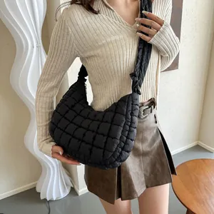 Détail du sac nuage noir matelassé avec bandoulière plissée porté à l'épaule croisée