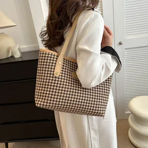Close-up of houndstooth tote bag featuring premium leather trim and gold rivet details