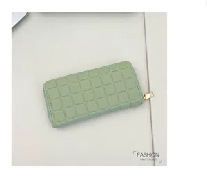 Macro detail of the embossed square texture and golden zipper on the bean green lady's purse