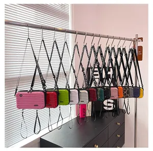 Mini suitcase-style crossbody bag showing 14 available colors and wide letter straps