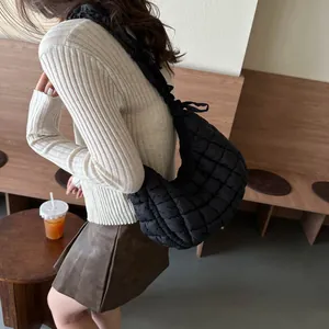 Fashionable black quilted cloud bag with ruffled shoulder strap shown on a model