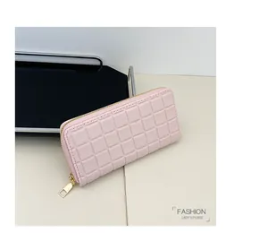 Detail of light pink long wallet with checkered pattern and gold zipper on a tray