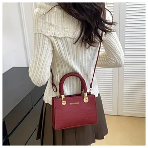 Red crocodile texture shoulder bag with golden ring handles shown on a model