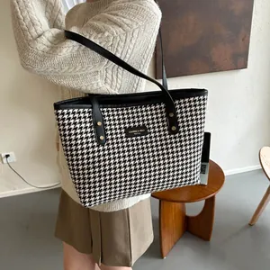 Detail of classic black and white houndstooth tote bag with leather straps on a shoulder