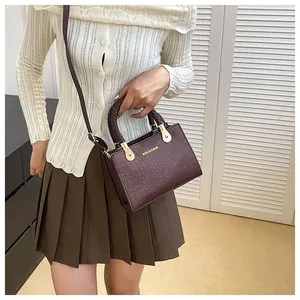 Detail of dark brown crocodile texture crossbody bag paired with a pleated skirt