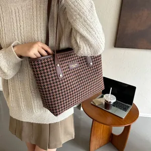 Close-up of houndstooth tote bag with brown leather handles in a cozy office setting