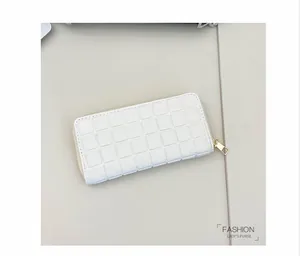 Detail of white long wallet with square quilted texture and gold zipper hardware