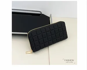 Detailed close-up of quilted square texture on black faux leather long wallet with gold zipper