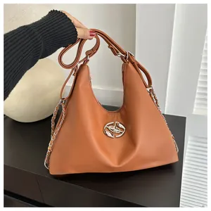 Detail of a brown PU leather half-moon bag with silver metal logo and chain strap