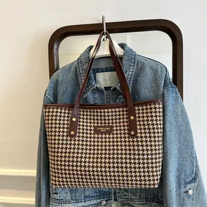 Detail of classic houndstooth tote bag with brown leather straps and rivet decoration