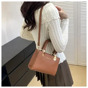 Detail of brown crocodile pattern handbag with gold hardware and woven handles